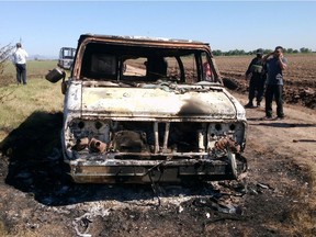 In this Nov. 21, 2015, file photo, Mexican authorities inspect a burnt out van suspected to belong to a couple of Australian tourists missing for more than a week, in Sinaloa, Mexico. Two burned bodies where reportedly found inside the vehicle. The tourists, Dean Lucas and Adam Coleman were traveling from Edmonton and were scheduled to arrive on Nov. 21 in the city of Guadalajara but failed to appear. Prosecutors in the Mexican state of Sinaloa said Friday, Dec. 4, they have detained three suspects in connection with their presumed killing.
