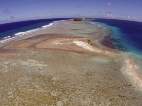 This Nov. 5, 2015 aerial photo shows a small uninhabited island that has slipped beneath the water line only showing a small pile of rocks at low tide on Majuro Atoll in the Marshall Islands.