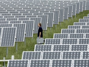 This file picture shows a technician walking past solar modules at the Solarpark Muehlhausen photovoltaic power plant in Muehlhausen, southwestern Germany.