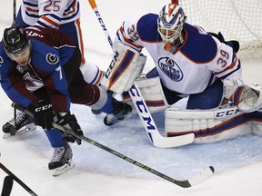 Colorado Avalanche centre John Mitchell, left, uses his stick to sweep the puck toward Edmonton Oilers goalie Anders Nilsson on Dec. 19, 2015, in Denver.