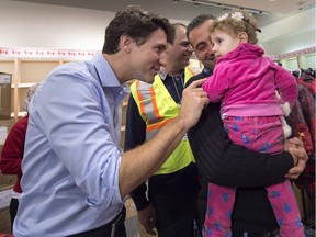 Canadian Prime Minister Justin Trudeau greets 16-month-old Madeleine Jamkossian, right, and her father Kevork Jamkossian, refugees fleeing the Syrian civil war, during their arrival at Toronto's Pearson International Airport on Dec. 11, 2015.