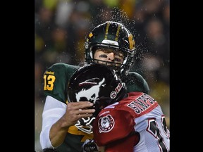 Edmonton Eskimos quarterback Mike Reilly (13) gets hit by Calgary Stampeders' Juwan Simpson during CFL action at Commonwealth Stadium on Sept. 12, 2015.