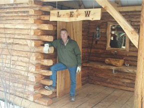 Larry Wozney poses outside an outhouse he built, complete with sliding doors, electricity and plumbing.
