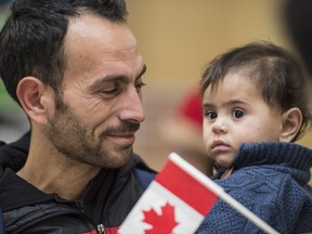 Sami Al Haidar holds his one-year-old son Mohammad. The Syrian refugee family  arrived in Edmonton on Saturday. The family was surviving in a camp in Lebanon.