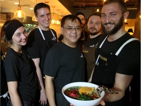 Chef Eric Hanson holds up a Roasted Barley Chicken Bowl ($15) with some of the other staff at Prairie Noodle House.