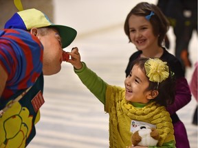 Refugee Karima, 4, gets enjoyment from squeezing the red nose of Choo Choo the clown as refugees and sponsor family members gathered at city hall for a welcome ceremony by officials and representatives from a variety of agencies in Edmonton,January 8, 2016.