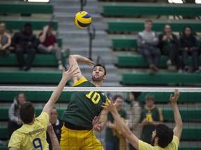 Taylor Arnett of the University of Alberta Golden Bears winds up at the net against Joel Regehr and Irvan Brar of the UBC Thunderbirds at the Saville Sports Centre.