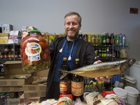 Store clerk Oleksiy Karpenko displays tomatoes and smoked skumbria, staple items at  Ukrainian Christmas.