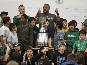 Edmonton Eskimos football players Grant Shaw (back left), D'Anthony Batiste (middle) and Ryan King (not shown in photo) brought the Grey Cup to a presentation on teamwork at L.Y. Cairns School on Jan. 15, 2016. The Eskimos talked to the students about the importance of being resilient and working hard with others to achieve a goal like winning the Grey Cup.