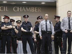 Police and security guards stand outside Edmonton council chambers to prevent angry taxi drivers from entering on Jan. 26, 2016.