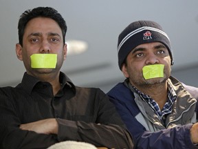 Yellow Taxi drivers (left) Harjinder Badesha and Anil Prasher taped their mouths shut in protest while attending Edmonton city council's meeting Tuesday.