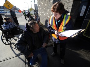 Volunteer Dorian Smith asks questions of homeless woman Gloria Bone, 56, for the Oct. 15, 2014 homeless count in front of Edmonton's Bissell Centre.
