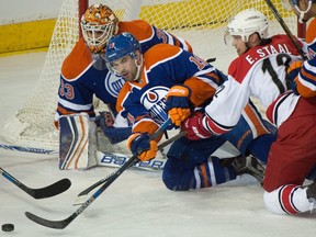 Goalie Cam Talbot (33) makes a save and Justin Schultz (19) knocks the puck away with Eric Staal (12) in front as the Carolina Hurricanes play the Edmonton Oilers in Edmonton, Jan. 4, 2016.