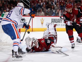 Goaltender Louis Domingue of the Arizona Coyotes makes a diving save on a shot as Lauri Korpikoski of the Edmonton Oilers looks for a rebound  at Gila River Arena on Jan. 12, 2016 in Glendale, Ariz.