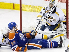 Nashville Predators goalie Pekka Rinne  makes a stick save with Edmonton Oilers forward Benoit Pouliot in close during NHL action at Rexall Place in Edmonton on Jan. 23, 2016.