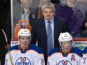 Edmonton Oilers head coach Todd McLellan stands on the bench behind Connor McDavid, left, and Ryan Nugent-Hopkins during  pre-season game against the Vancouver Canucks. Both players are out of the lineup with injuries.