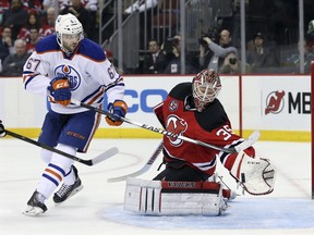 New Jersey Devils goalie Cory Schneider (35) makes a glove save on a shot by Edmonton Oilers left wing Benoit Pouliot (67) during the first period of an NHL hockey game Tuesday, Feb. 9, 2016, in Newark, N.J.