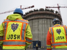 Construction workers look at the FortisBC Tilbury LNG expansion project in Delta, B.C., in November. The hot B.C. construction industry is luring workers from Alberta's stalled energy sector. File photo.