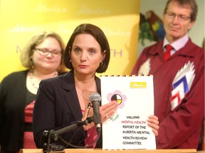 Danielle Larivee, Minister of Municipal Affairs and co-chair of the Alberta Mental Health Review, holds the report flanked by Health Minister Sarah Hoffman and co-chair David Swann at a press briefing in Calgary on Monday, Feb. 22, 2016.