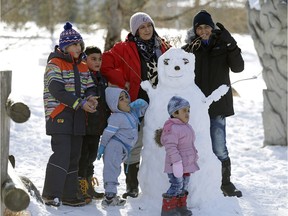 A refugee family stands beside a snowman at Rundle Park, where Edmonton's Winter Wonderland Welcome Festival was held for newcomers to the city on Saturday.