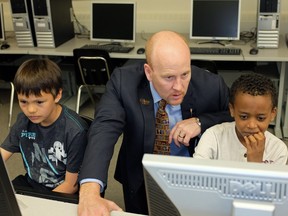 Former Alberta Education Minister Jeff Johnson (middle) interacts with grade 3 students Niklas Crane (left/9-years-old) and Eliyas Galmo (right/8-years-old) at Oliver School in Edmonton on May 9, 2013, where the Minister announced a new provincial computer-based student assessment testing program for schools in Alberta.