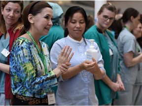 Renee Parsons gets some hand sanitizer from Liwayway Pacolor during a Guinness World record attempt at most staff members sanitizing their hands in one event at the Royal Alexandra Hospital in Edmonton on Oct. 15, 2015.