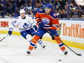Brandon Davidson (88) of the Edmonton Oilers carries the puck as Rich Clune (25) of the Toronto Maple Leafs comes up from behind during first period action at Rexall Place in Edmonton, Alta. on Feb. 11, 2016.