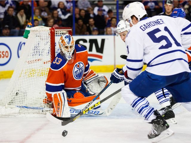 Goalie Cam Talbot (33) of the Edmonton Oilers keeps his eyes on the puck as Jake Gardiner (51) of the Toronto Maple Leafs charges at Rexall Place in Edmonton, Alta. on Feb. 11, 2016. 