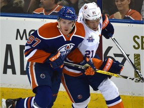 Edmonton Oilers Connor McDavid (97) and New York Islanders Kyle Okposo (21) go after the puck during NHL action at Rexall Place in Edmonton, February 28, 2016.