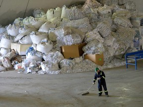 An employee sweeps the floor in front of a pile of recycled paper at the Greys Paper Recycling Industries Ltd. facility in Edmonton on May 16, 2013. The plant filed for bankruptcy last month.