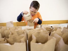 Mateo Daza Cardona, 9, and Grade 5 students from St. James Catholic Elementary School packs bag lunches for less fortunate elementary school students, at Millhurst Community Hall in Edmonton.