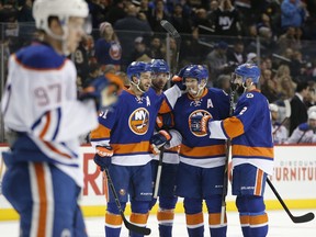 Edmonton Oilers forward Connor McDavid, left, skates away as New York Islanders teammates celebrate with right wing Kyle Okposo (21) after Okposo scored a goal in the second period of an NHL hockey game in New York on Feb. 7, 2016.