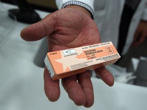 A pharmacist store holds a box of the drug overdose antidote naloxone. Naloxone can temporarily block the effects of fentanyl, heroin, OxyContin and other painkillers.