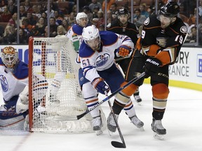 Edmonton Oilers cenre Anton Lander, middle, fends off Anaheim Ducks forward Patrick Maroon, right, during NHL action on Feb. 26, 2016, in Anaheim, Calif.