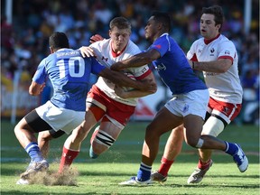 John Moonlight of Canada (C) is tackled by Samoa Toloa and Tomasi Alosio of Samoa in the Bowl final at the Sydney Sevens rugby union tournament in Sydney on Feb. 7, 2016.