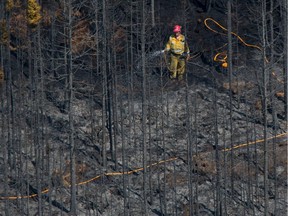 Woodland fire fighters with Alberta Agriculture and Forestry extinguish hot spots in a wildfire approximately 22 kilometres east of Slave Lake Alta. on May 27, 2015.