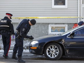 Edmonton Police Service officers investigate a damaged Chrysler 300 after a shooting involving multiple suspects near 159 Street and 103 Avenue in Edmonton, Alta., on Sunday February 28, 2016.
