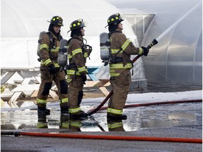 Firefighters douse hot spots following a fire at the Alberta Hospital greenhouse section.