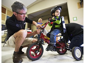 Bicycle mechanic Jonathan Woelder, left, makes adjustments to a tricycle ridden by Charlie Ross, 3, during a bicycle fitting day for children with special needs put on by You Can Ride 2 at the Robin Hood Children and Youth Centre in Sherwood Park, Alta., on Saturday, April 11, 2015. Codie McLachlan
