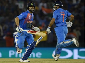 India's captain Mahendra Singh Dhoni(R)and teammate Virat Kohli run between the wickets during the World T20 cricket tournament match between India and Australia at The Punjab Cricket Stadium Association Stadium in Mohali on March 27, 2016.