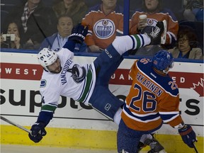 Edmonton Oiler Iiro Pakarinen hits Vancouver Canucks Matt Bartkowski into the boards during first period NHL action on March 18, 2016 in Edmonton.