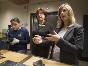 Tessa Minde uses metal cutters to create a metal rose as JudyLynn Archer, President and CEO, Women Building Futures and Status of Women Minister, Stephanie McLean tour the metal shop at the Woman Building Futures Society on March 7, 2016, in Edmonton.