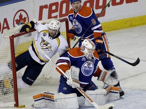 Edmonton Oilers goalie Laurent Brossoit makes a save as Nashville Predators Austin Watson crashes into the net during second period NHL hockey game action in Edmonton on Monday March 14, 2016. Oilers defenceman Griffin Reinhart is in background.