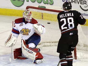 Edmonton Oil Kings goalie Payton Lee and Red Deer Rebels' Adam Helewka watch the puck go into the net on a shot by Rebels defenceman Colton Bobyk during WHL action in Edmonton on March 17, 2016.