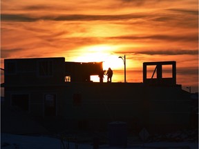 Workers stand atop a home under construction in southwest Edmonton.