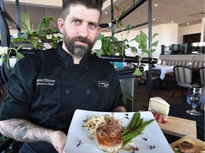 Chef Jason Oliver stands in front of an aquaponic edible garden at the Farm to Fork restaurant in Sherwood Park,  holding a pork loin dish.