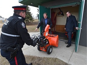 Police officers Const. Uwe Steil (centre) and acting Sgt. Ron Smithman (left) return close to $12,000 in recovered snow-cleaning equipment stolen from the North Millbourne Community League hall as league vice-president Brandon Kowalczyk watches in Edmonton, March 15, 2016.