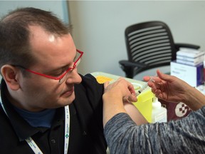 Dr. Chris Sikora, Medical Officer of Health for the Edmonton Zone of Alberta Health Services, gets his immunization shot from registered nurse Sandra  Byers in Edmonton, October 20, 2015.