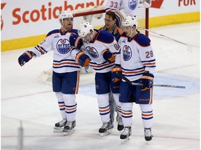 Edmonton Oilers' Matt Hendricks (23) and Lauri Korpikoski (28) assist Brandon Davidson (88), middle, after he collided awkwardly with Winnipeg Jets' Dustin Byfuglien (33) during first period NHL hockey action, in Winnipeg on Sunday, Mar. 6, 2016.