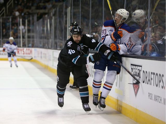 SAN JOSE, CA - MARCH 24: Roman Polak #46 of the San Jose Sharks checks Connor McDavid #97 of the Edmonton Oilers at SAP Center on March 24, 2016 in San Jose, California.